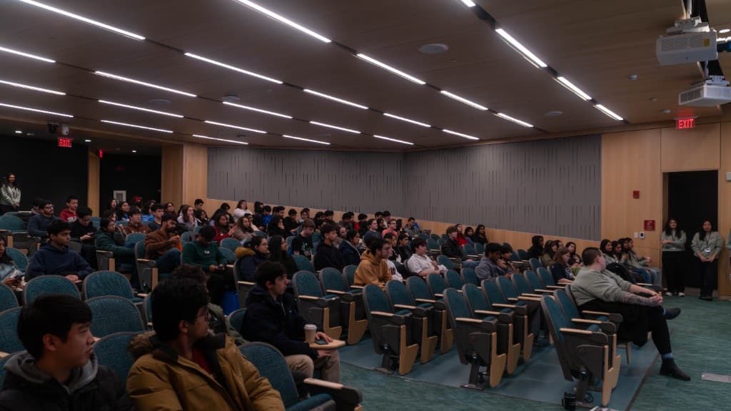 A full auditorium of attendees seated for a hackathon ceremony.